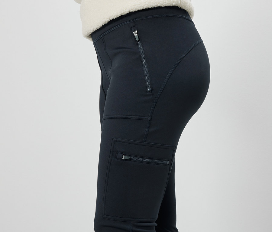 Siyah, fermuarlı cepleri olan pantolon giyen bir kadının yandan görünümü.