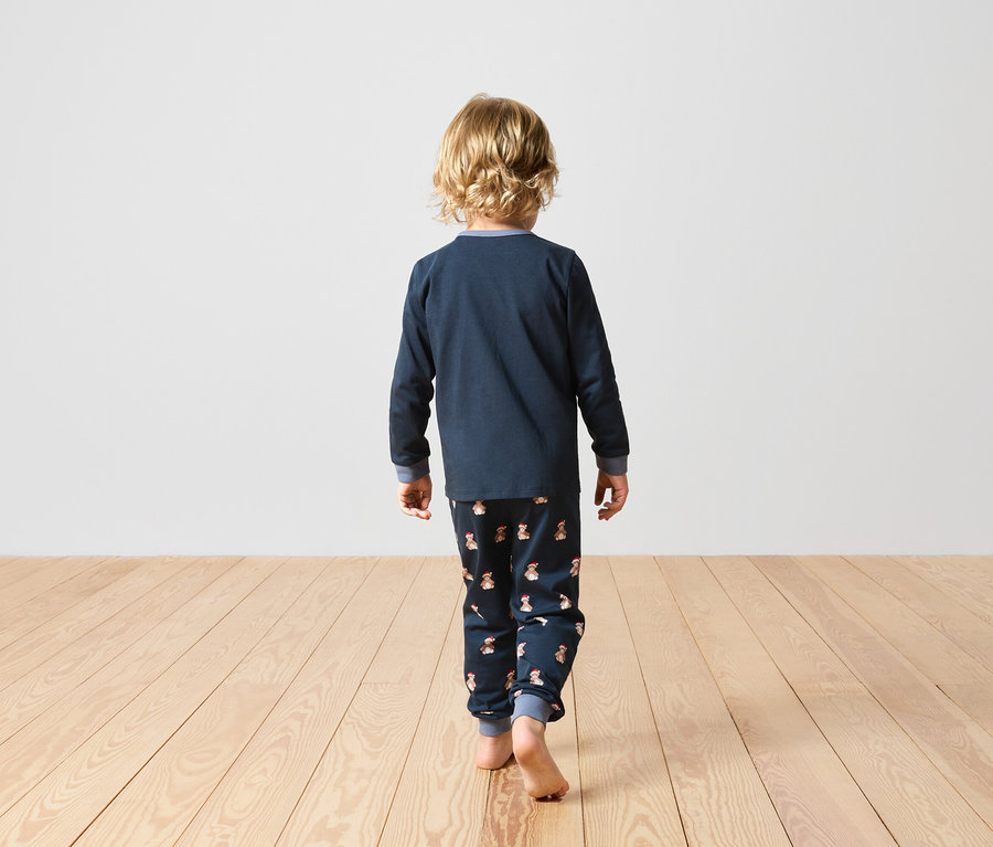 Tavşan desenli lacivert pijamalı bir çocuk arkası dönük duruyor.