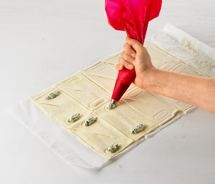 Bir el, Kruvasan Rulosu ile hamuru dolgu ile dolduruyor.