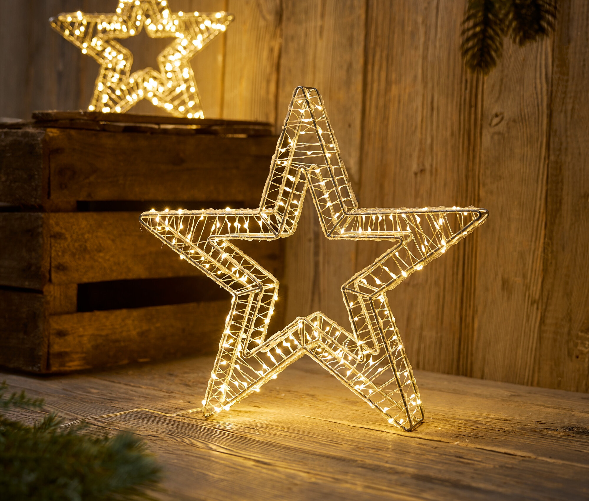 LED ışıklı iki dekoratif yıldız ahşap bir yüzey üzerinde duruyor.