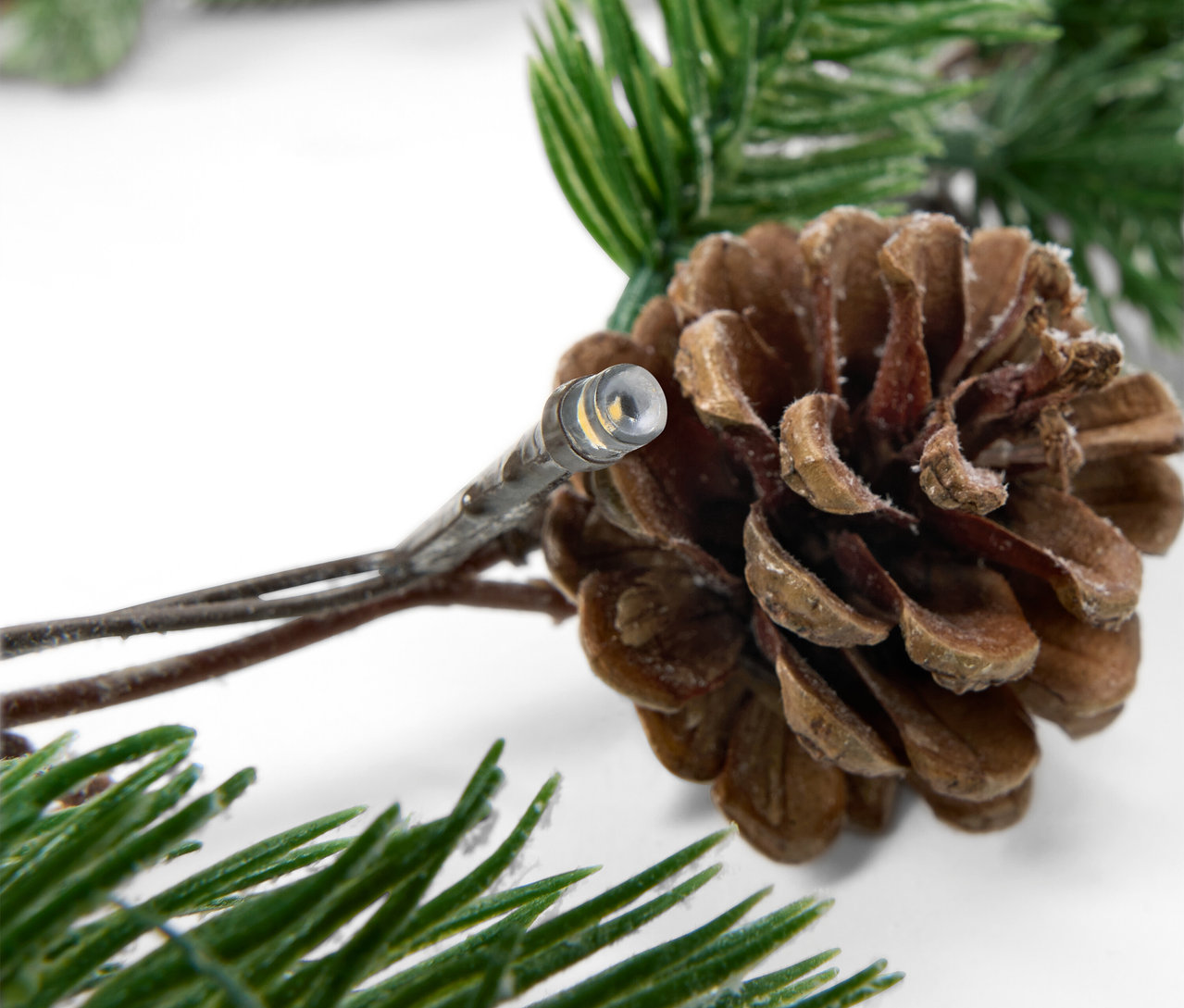 Kozalak ve çam dallarıyla ışık zinciri detayı.