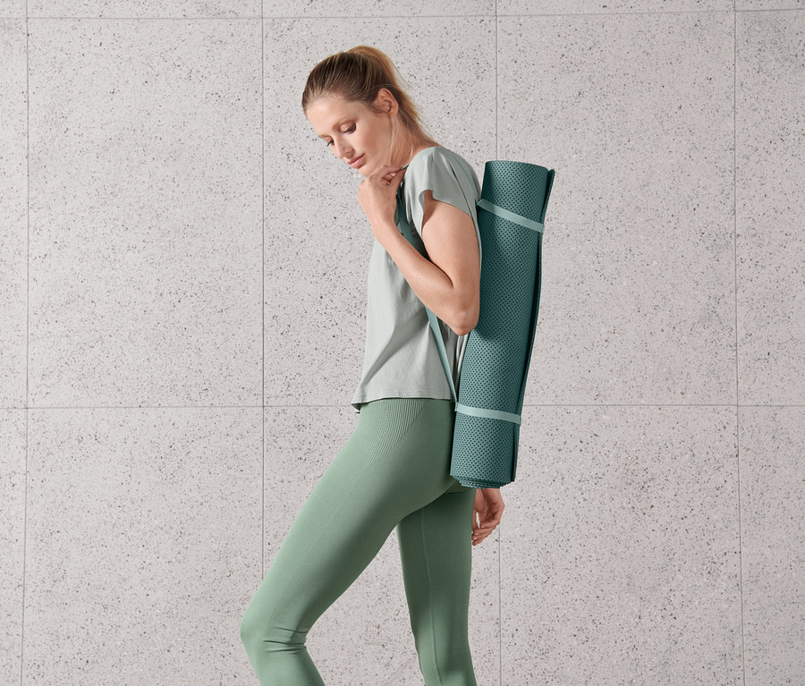 Kadın bir yoga ve fitness matı taşıyor.