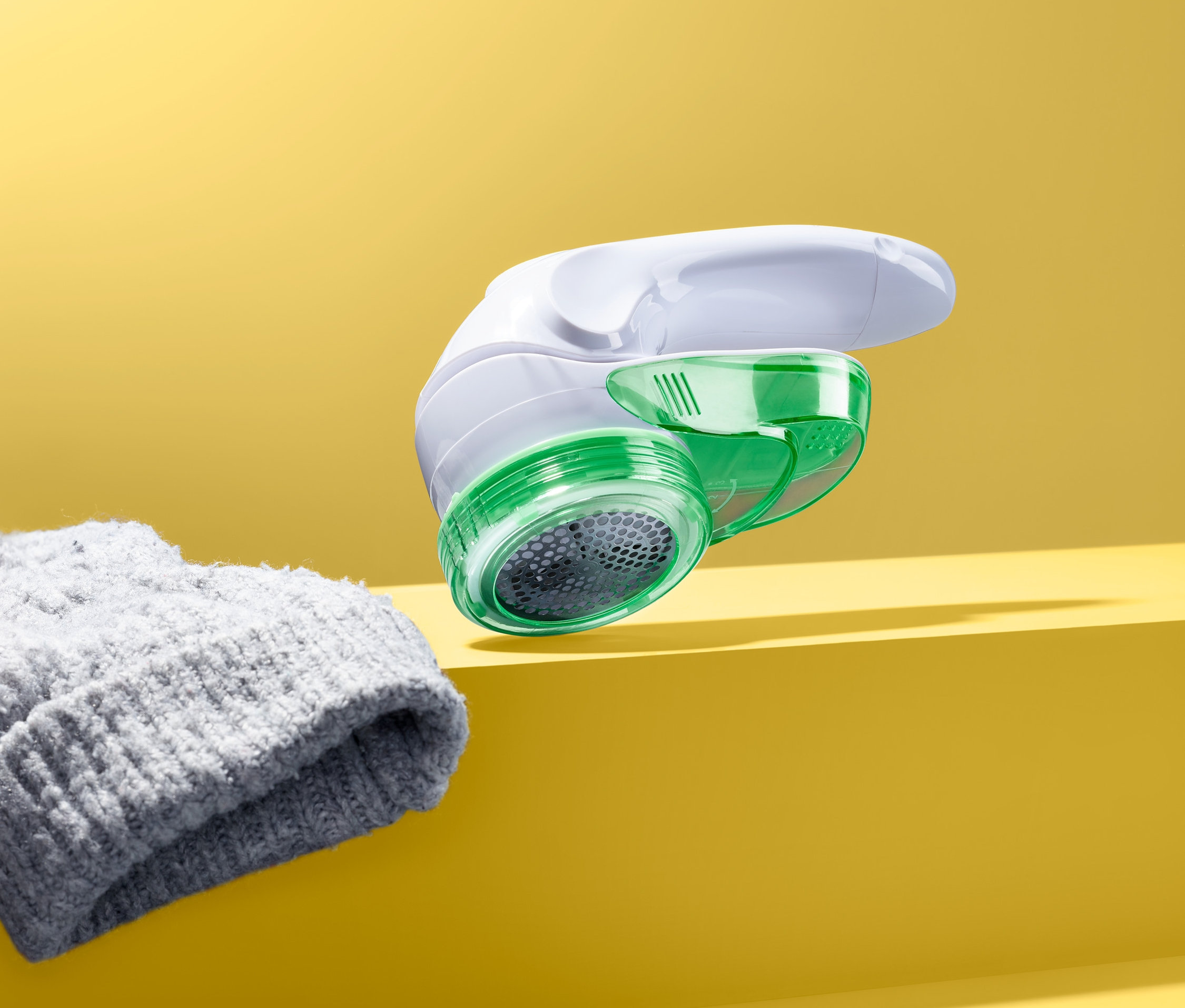 Döner başlıklı tiftik toplama makinesi sarı bir arka planda gri bir örgü şapkanın yanında duruyor.