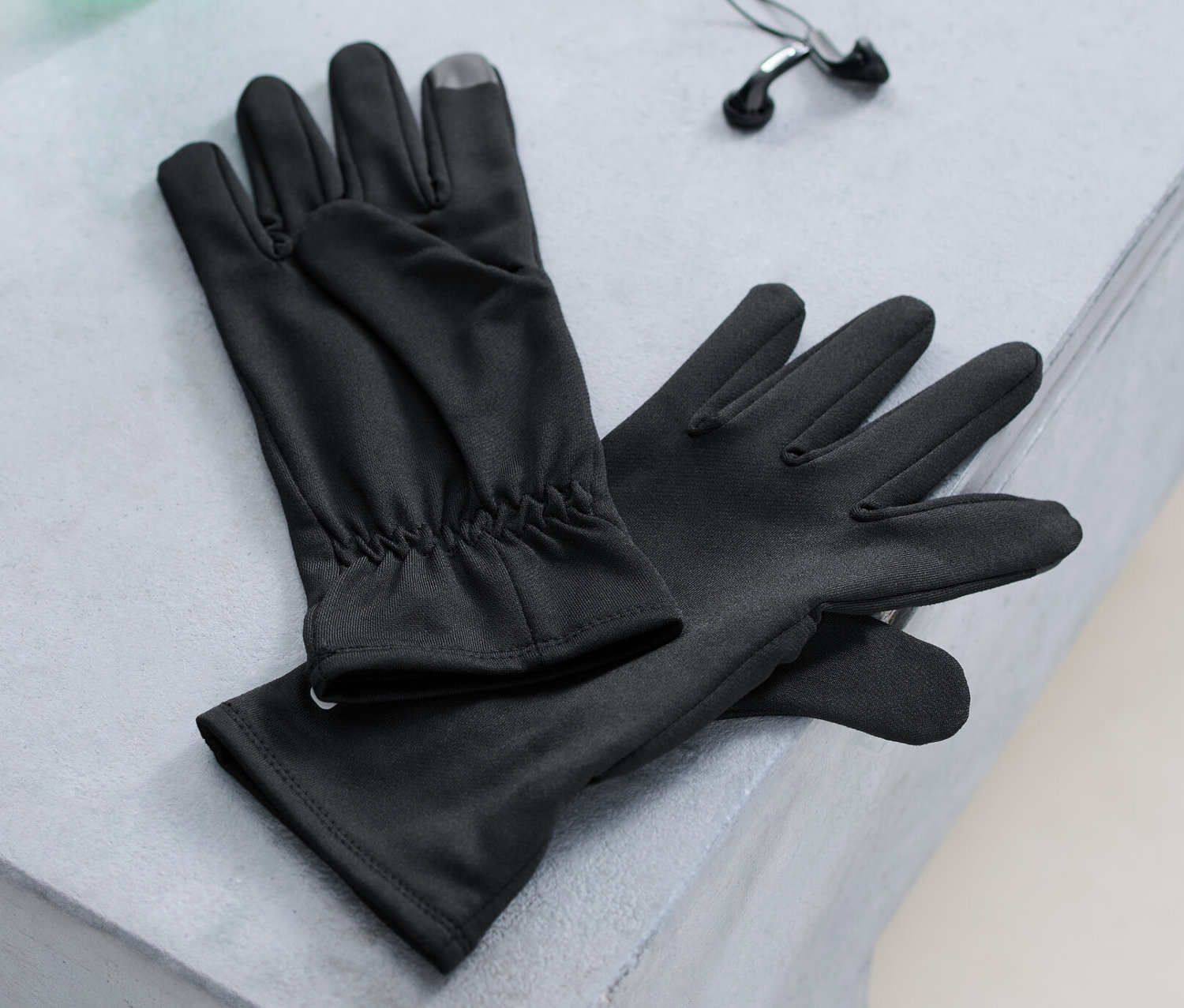 Bir bankta koşu eldivenleri, bir su şişesi ve kulaklıklar duruyor.