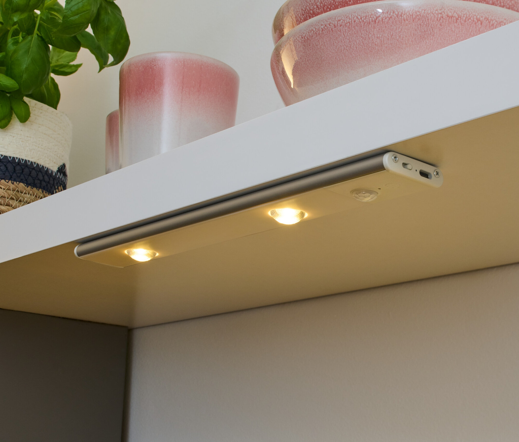 Bir rafın altına monte edilmiş şarjlı çok işlevli LED lamba, bir tezgahı aydınlatıyor.