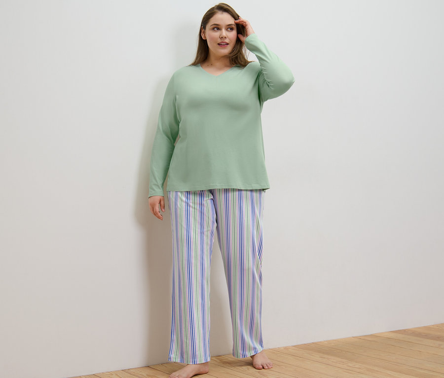 Kadın Pijama Takımı giyiyor ve bir odada duruyor.