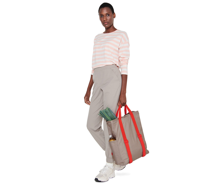 Kadın, içinden sebzeler ve bir şişe sarkan bir piknik sırt çantası tutuyor.