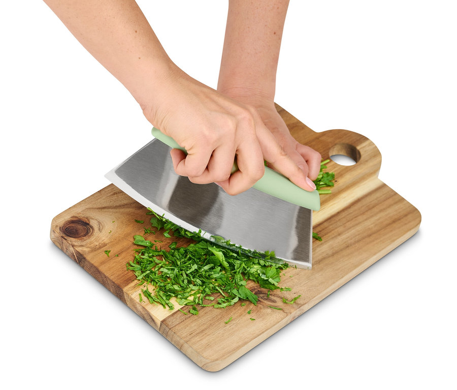 Eller tahta bir tahtada pizza ve yeşillik kesici ile otları kesiyor.