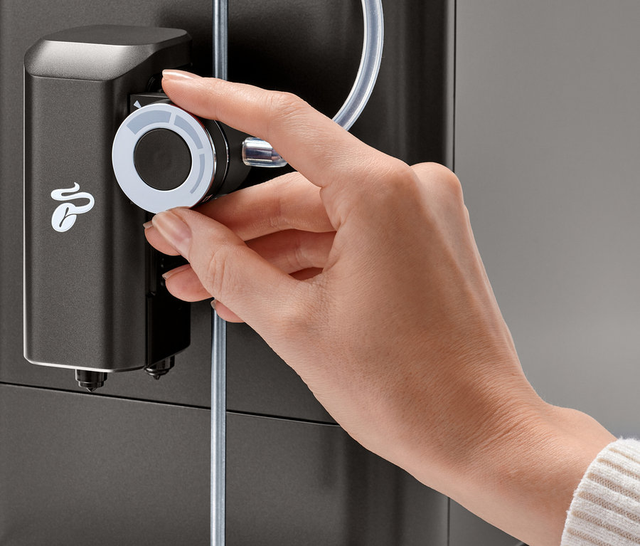 Bir el, Tchibo »Esperto 2 Milk« Granite Black kahve makinesinin süt köpüğü ayar düğmesini çeviriyor.