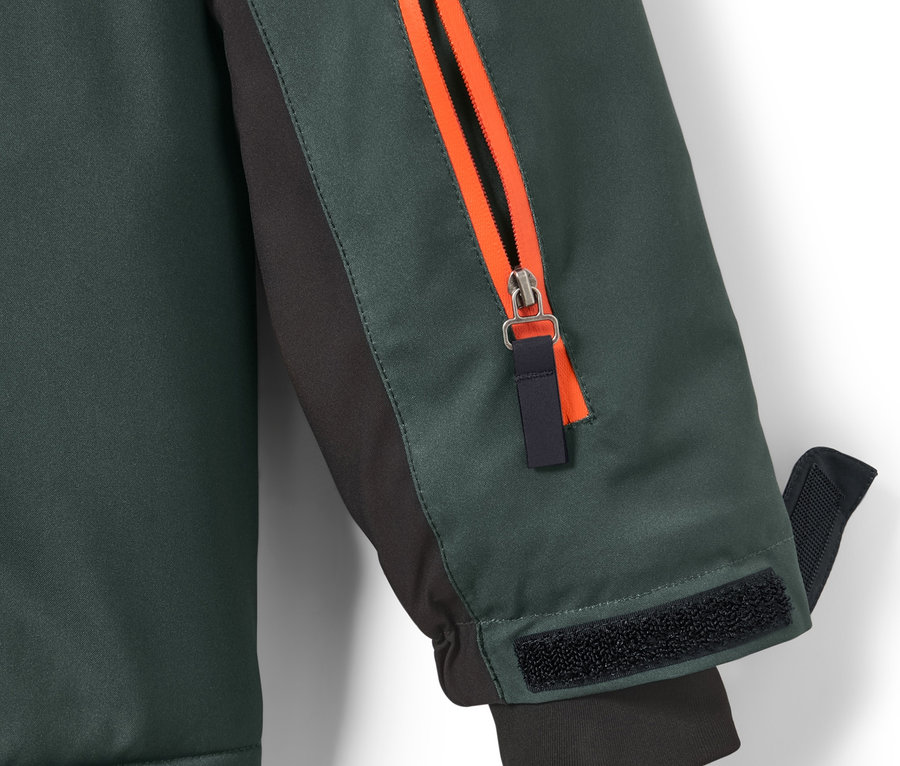 Kolunda turuncu fermuarı olan çocuk kayak montu detayı.