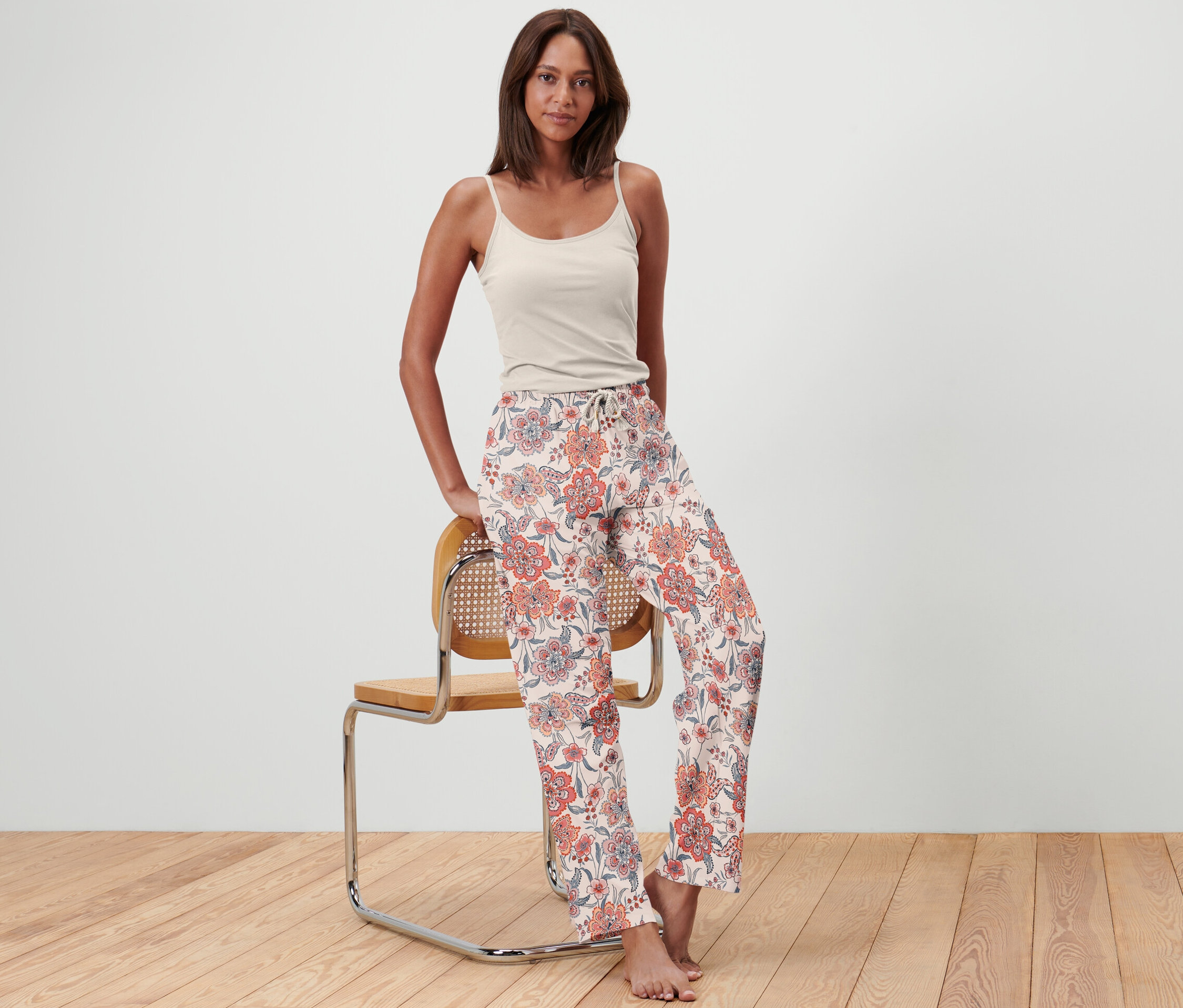 Kadın bir sandalyeye yaslanmış, üzerinde pijama altı var.