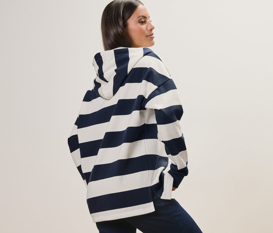 Çizgili kapüşonlu sweatshirt giyen bir kadın poz veriyor