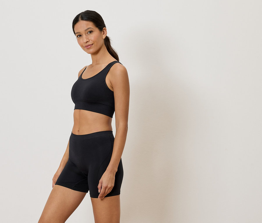Kadın siyah bir sporcu sütyeni ve şort giyiyor.