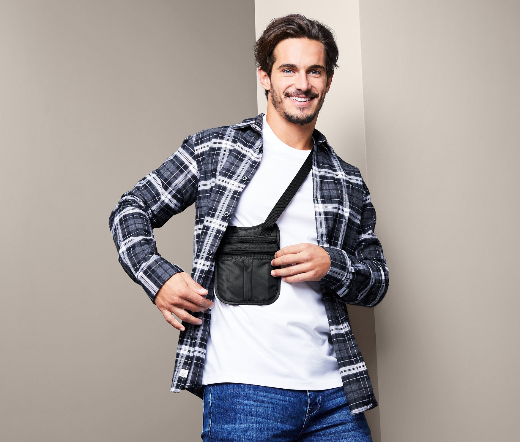 Kahverengi saçlı bir adam, siyah omuz kemerli güvenli çantayı çapraz vücudunda taşıyor.