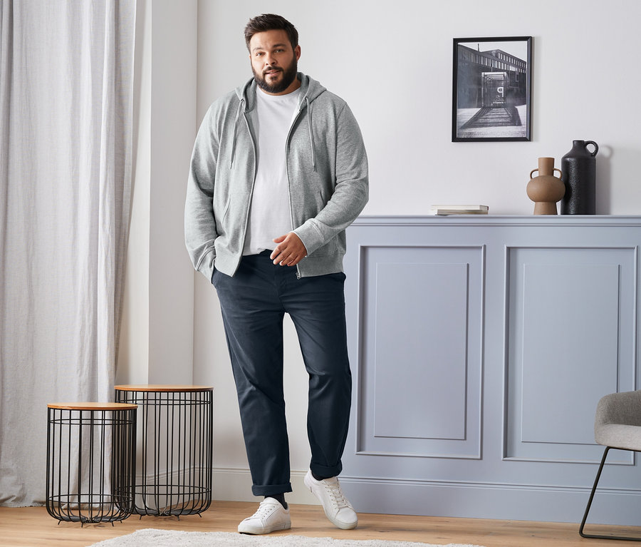 Bir adam gri bir sweatshirt ceket, beyaz bir tişört, mavi chino pantolon ve beyaz spor ayakkabılar giyiyor. Ayrıca siyah, lacivert, antrasit ve gri renklerde 4 çift merinos yünü çorap bulunmaktadır.