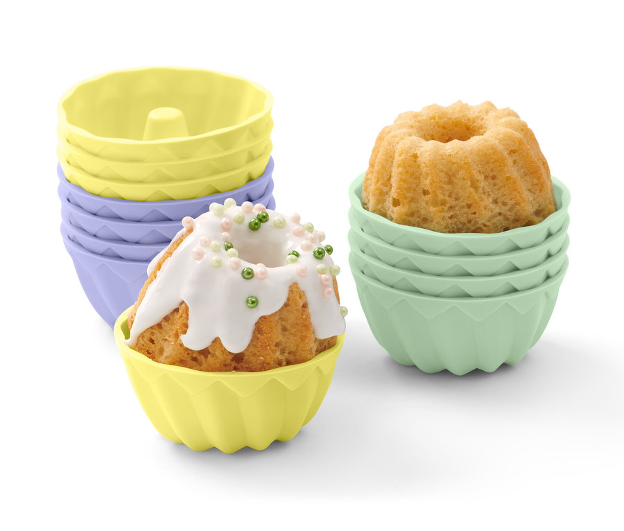 Sarı kalıpta, beyaz kremalı ve renkli boncuklarla süslenmiş mini kek. Arka planda 12 adet Mini Delikli Kek Kalıbı.