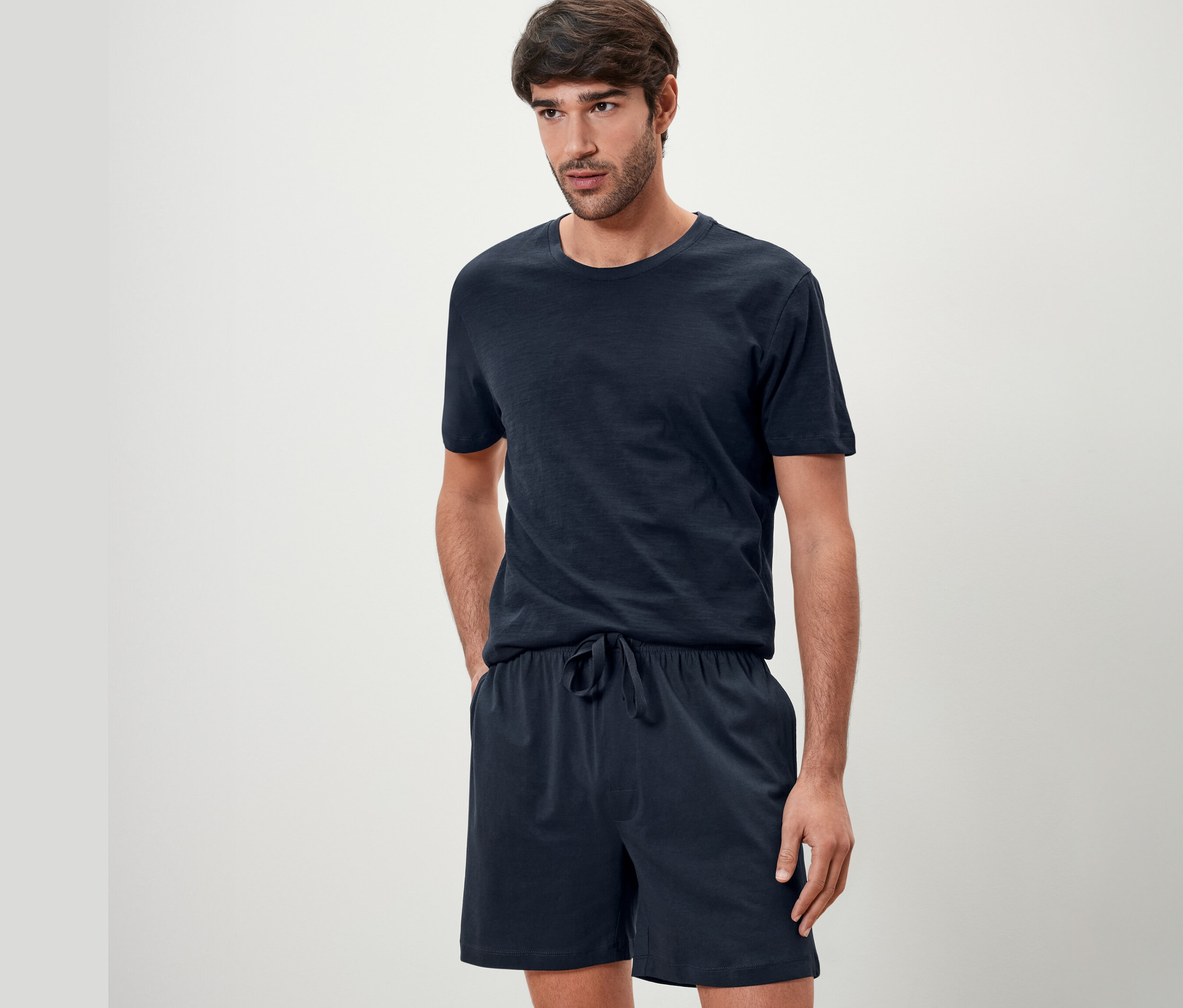 Lacivert Şortlu Pijama Takımı giyen bir adam poz veriyor.