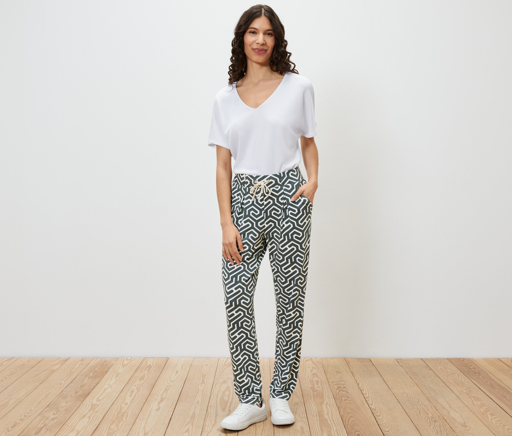 Kadın yeşil baskılı jarse pantolonla poz veriyor.