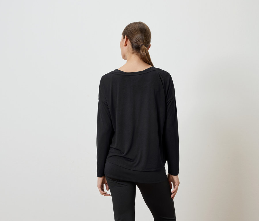 Siyah uzun kollu bluz ve siyah pantolon giyen bir kadının arkadan görünümü.