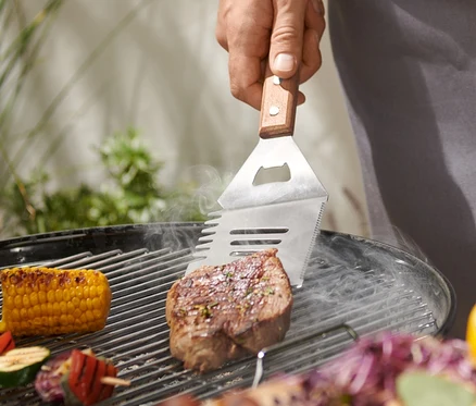 Adam çok amaçlı BBQ aletiyle biftek ızgara yapıyor.