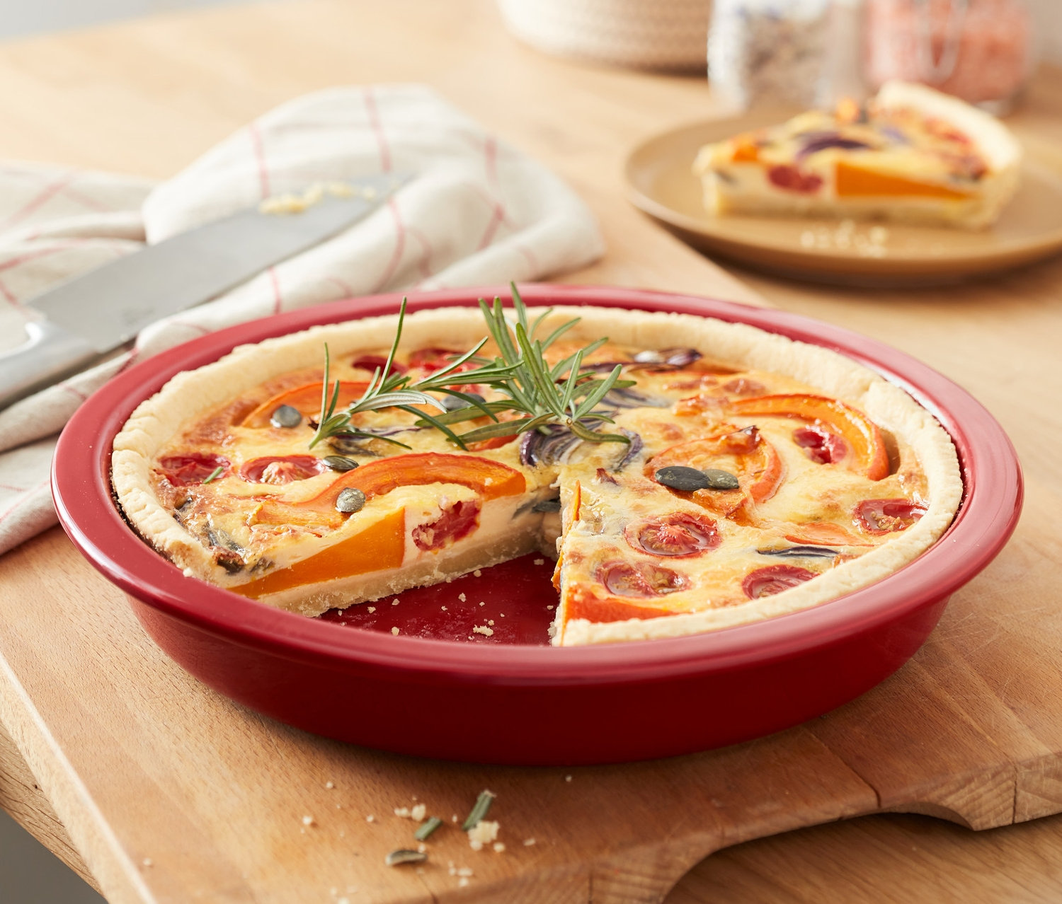 Ahşap bir masanın üzerinde, bir dilimi kesilmiş kırmızı turta kalıbı.