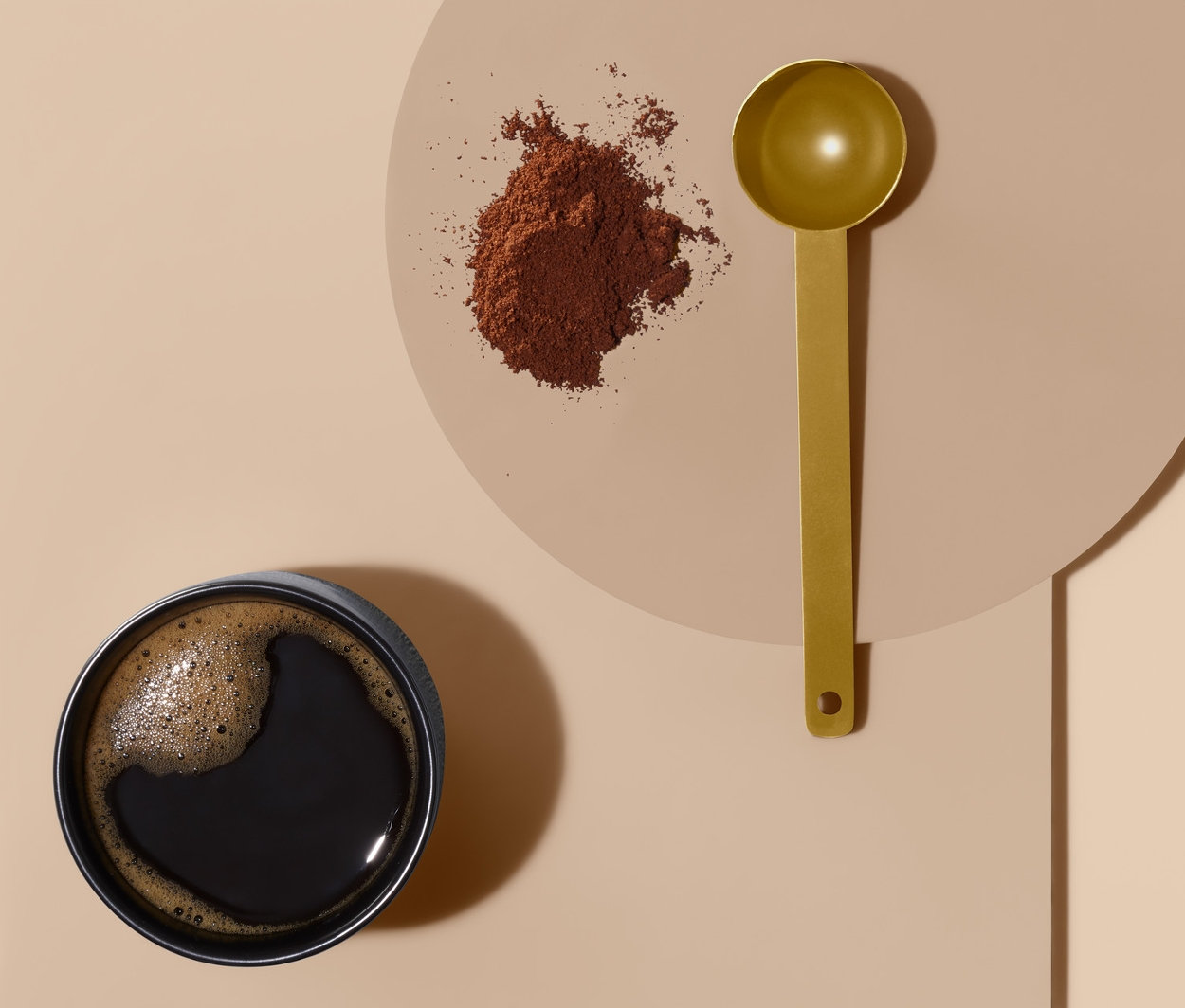 Bir fincan kahve, bir yığın çekilmiş kahve ve bir kahve ölçü kaşığı.