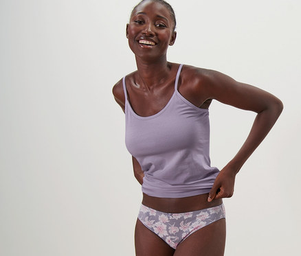 Gülümseyen bir kadın atlet ve 5 adet slip külotla poz veriyor.