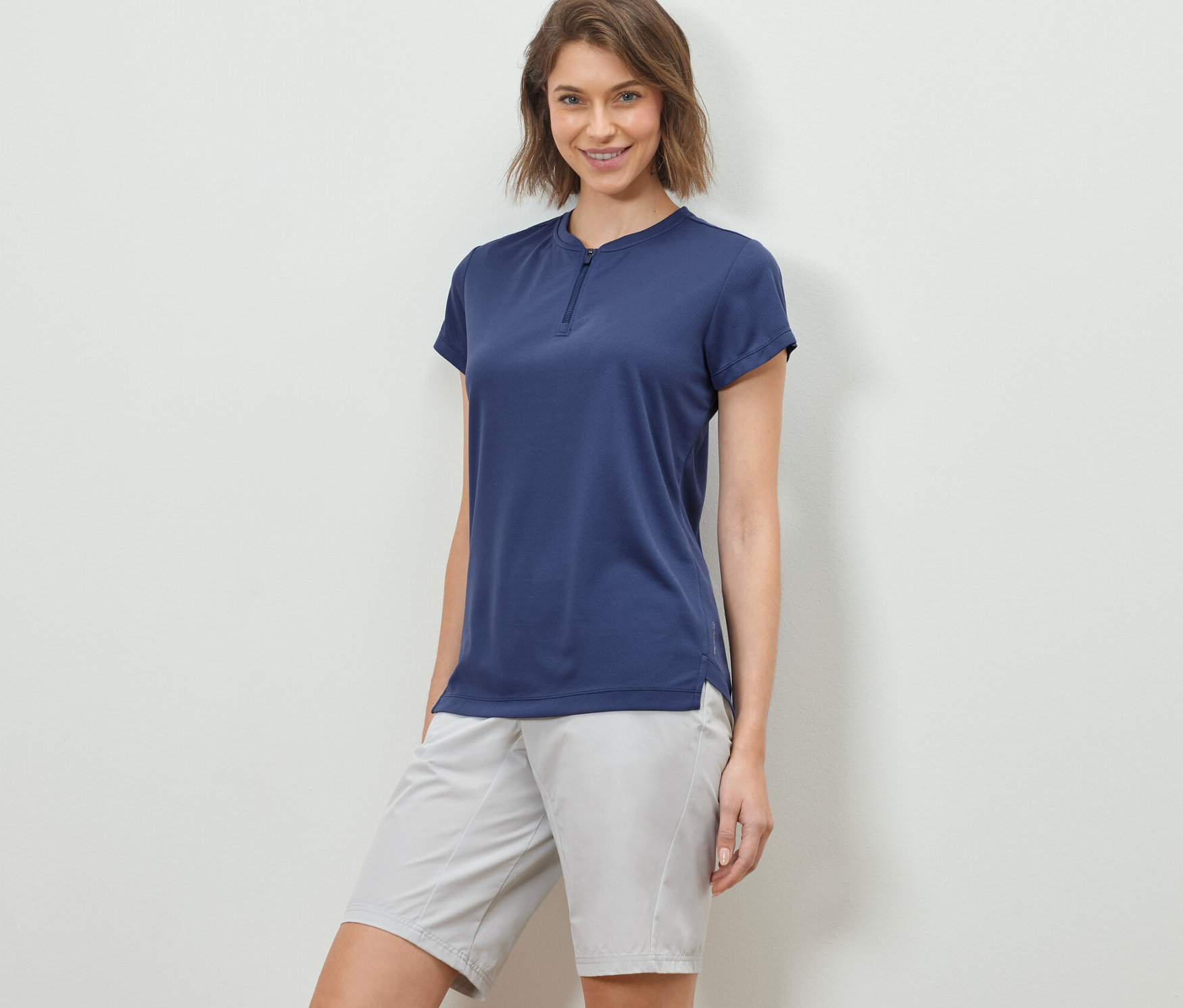 Kadın, Yarım Fermuarlı Spor Tişört ve şortla poz veriyor.