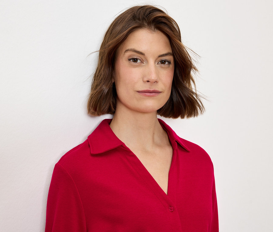 Kahverengi saçlı, kırmızı yakalı bluz giyen bir kadının portresi.