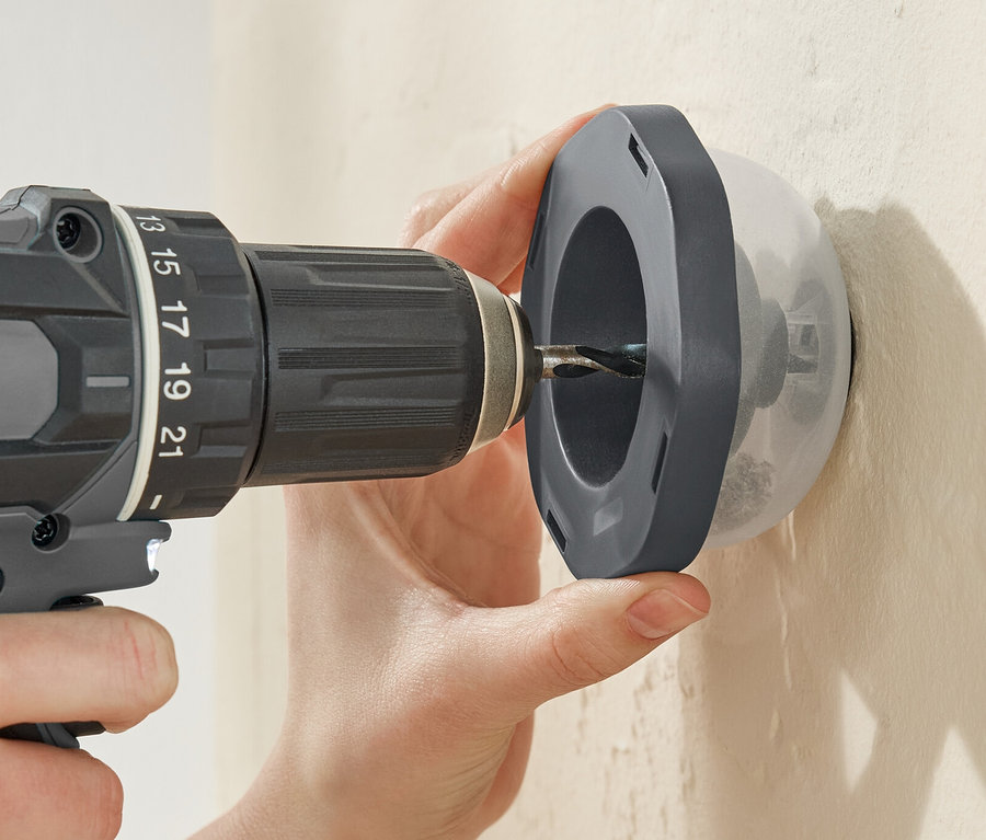 Bir kişi bir matkapla Bohrstaubfänger toz tutucu aracılığıyla bir duvarı deliyor.