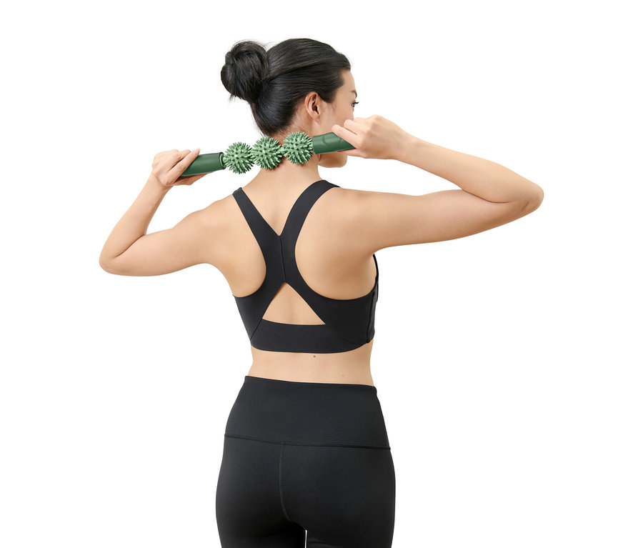 Kadın boynuna yeşil masaj aleti uyguluyor.