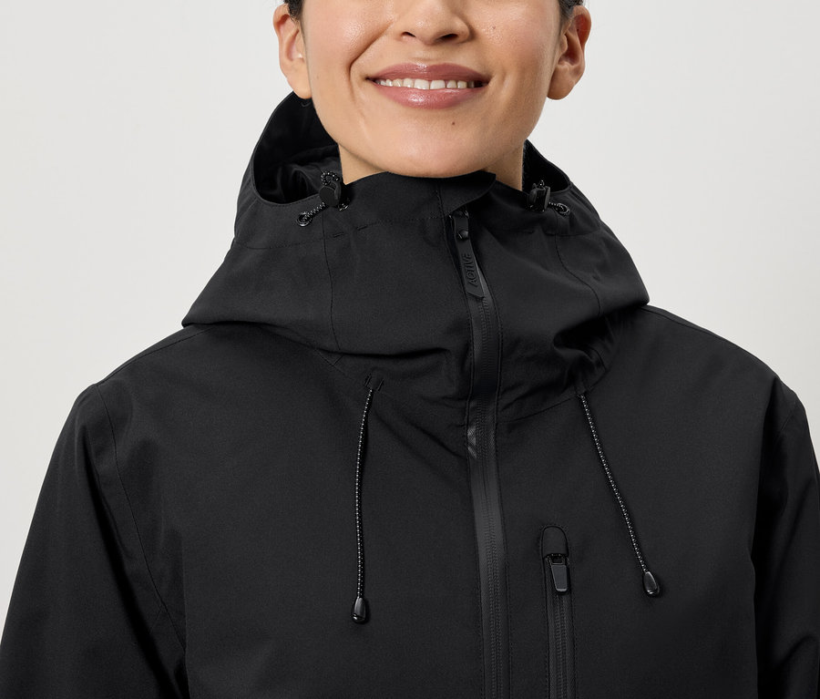 Gülümseyen bir kadın siyah kapüşonlu bir ceket giyiyor.