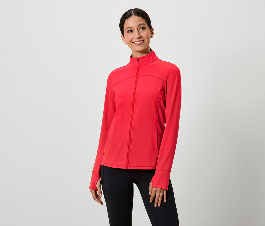 Kadın kırmızı fermuarlı ceket ve siyah tayt giyiyor.