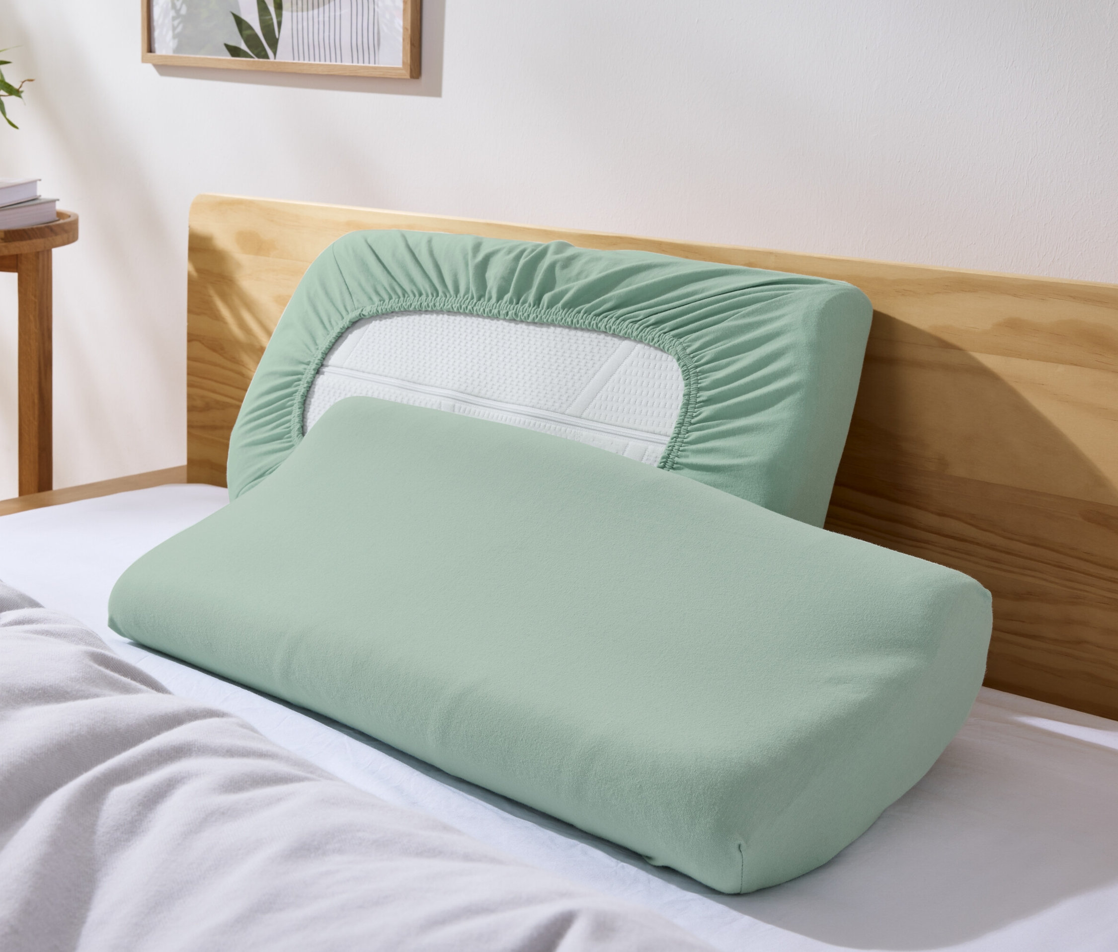 Yatakta duran iki adet yeşil jarse boyun yastığı kılıfı. 