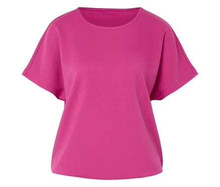 Düz bir yüzey üzerinde pembe, kısa kollu, yuvarlak yakalı bir tişört duruyor.