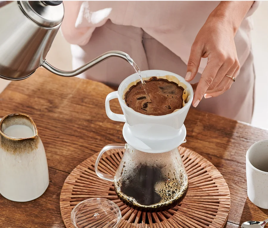 Kadın, demlikten beyaz Filtre Kağıdı No. 2, 18x 80 Adet ile Kaffee Handfilter Gr. 2, weiß içine su döküyor.