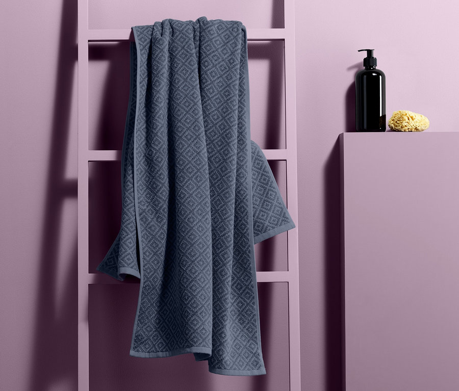 Jakarlı banyo havlusu, sabunluk ve süngerin yanında dekoratif bir merdivene asılıdır.