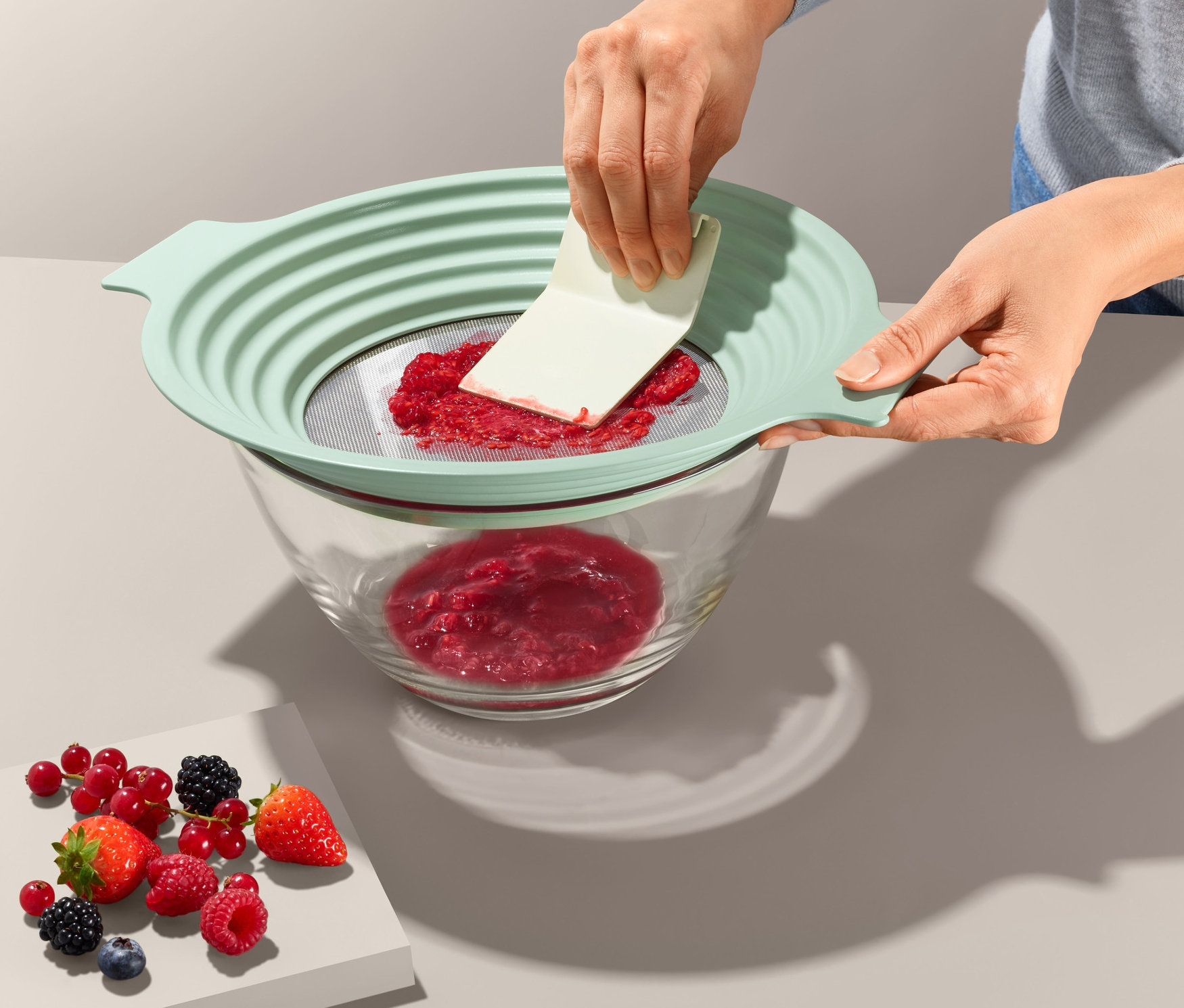 Kadın, 2'si 1 Arada Un Eleği ve Süzgeç ile ahududuları cam bir kaseye geçiriyor.