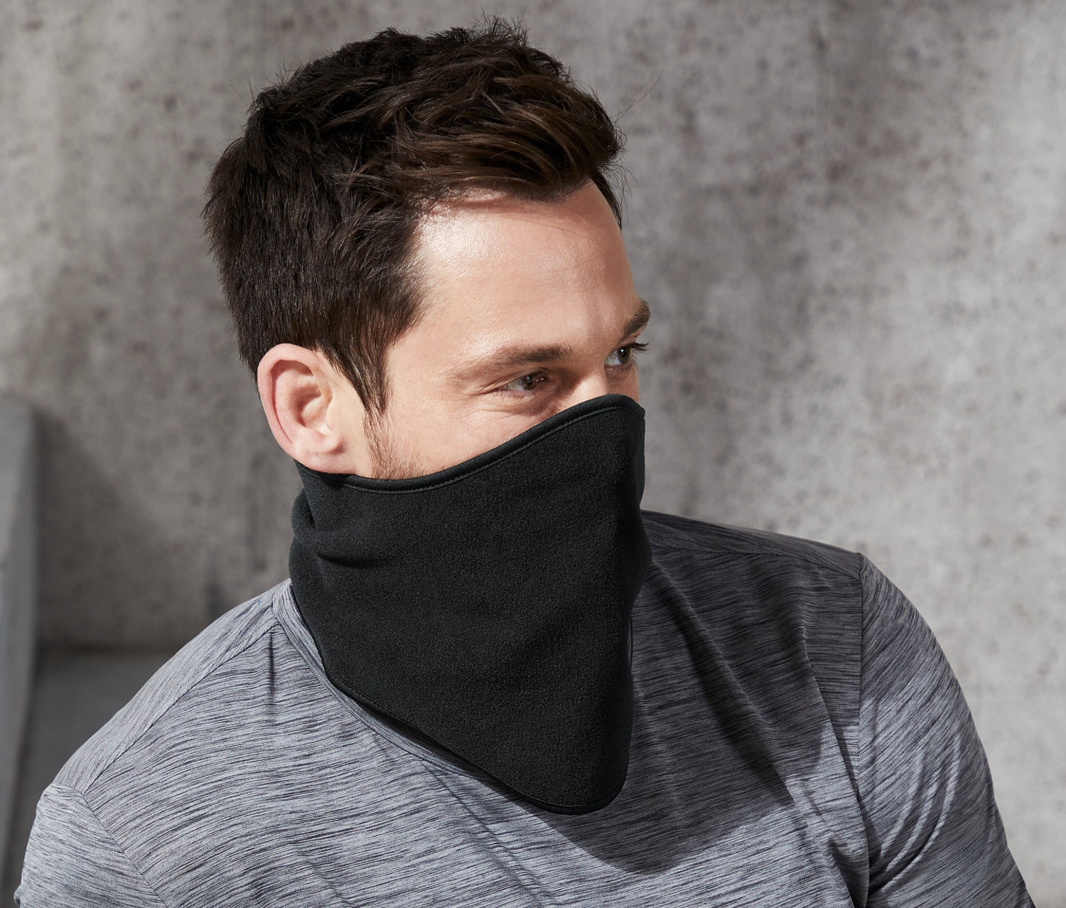 Adam oturuyor ve siyah soğuktan koruyan boyunluk takıyor.