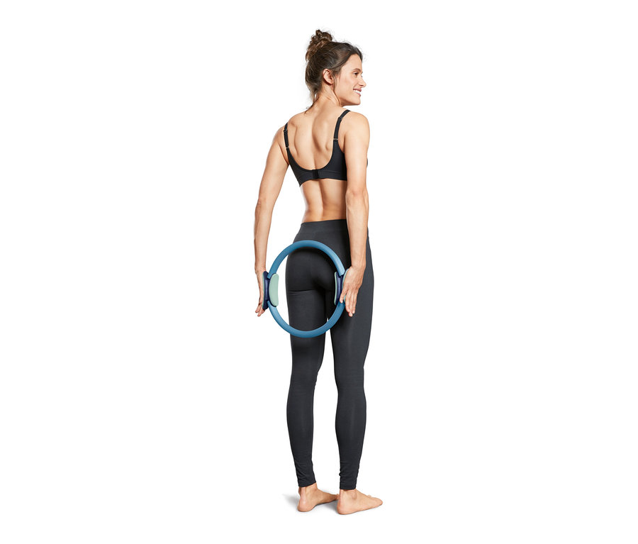 Kadın arkasında mavi bir Pilates Halkası tutuyor.