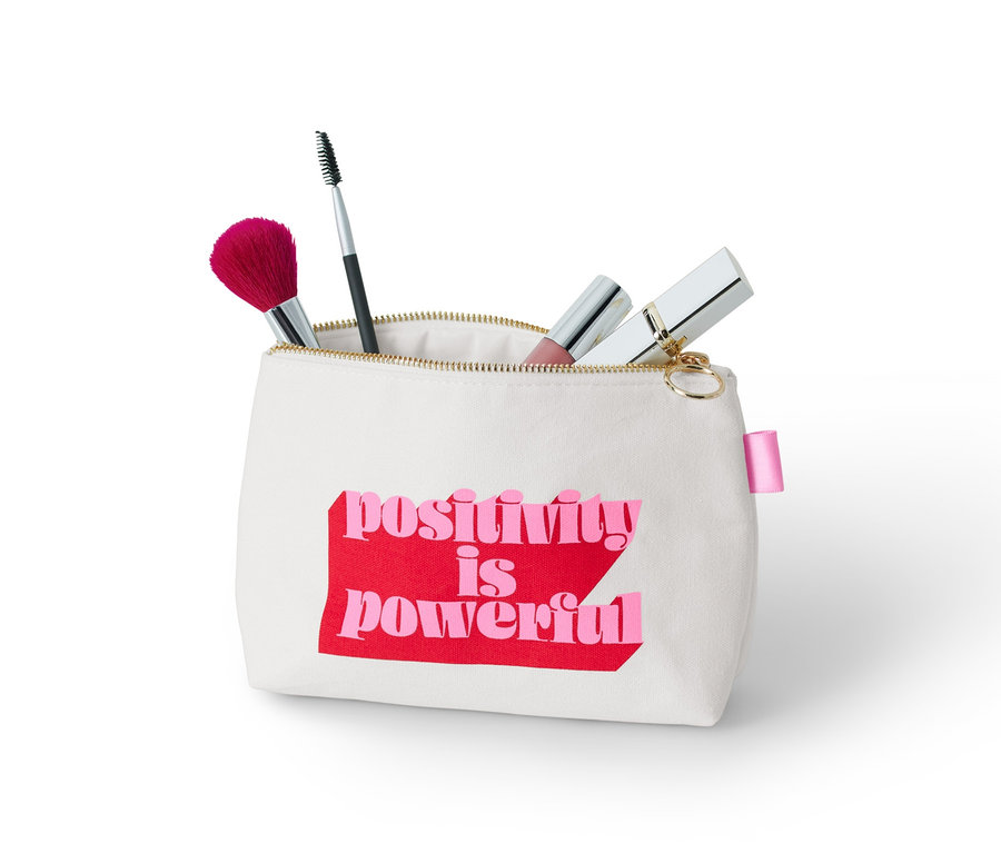 Üzerinde "positivity is powerful" yazısı olan bir makyaj çantası ve makyaj fırçaları.