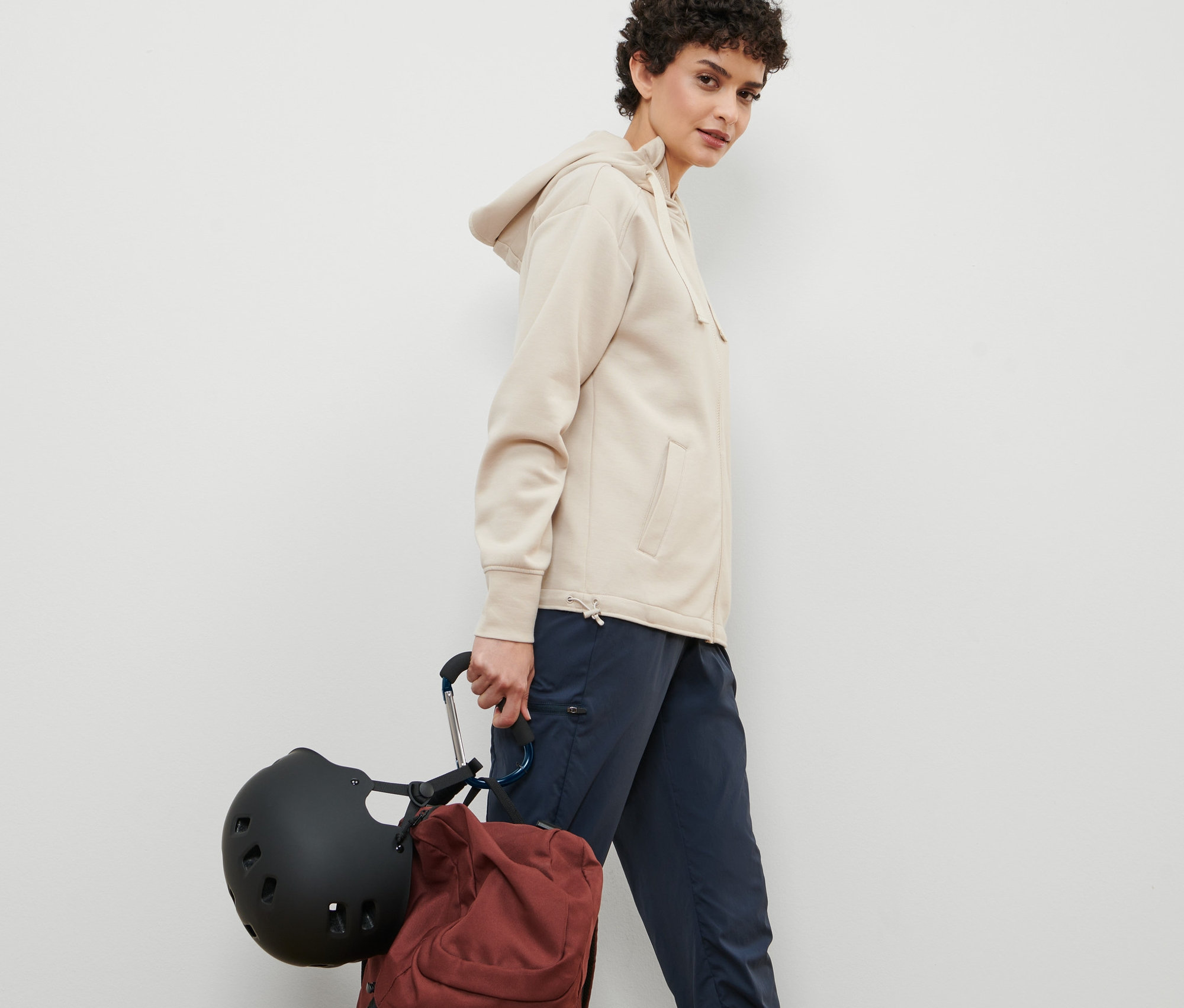 Kadın yürüyor ve 2 Adet XXL Karabina Kanca ile tutturulmuş bir kask ve sırt çantası taşıyor.