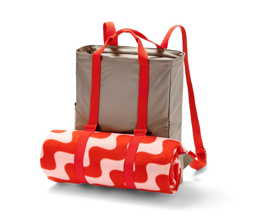 Kırmızı şeritlerle tutturulmuş, kırmızı desenli, rulo halinde bir battaniyeyle birlikte piknik sırt çantası.