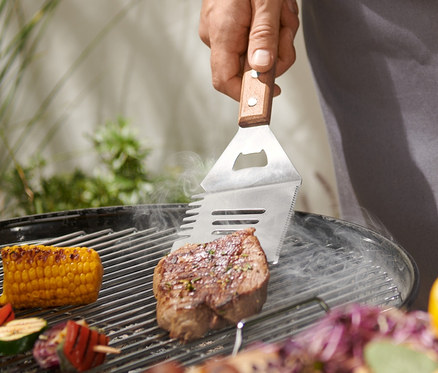 Adam çok amaçlı BBQ aletiyle biftek ızgara yapıyor.