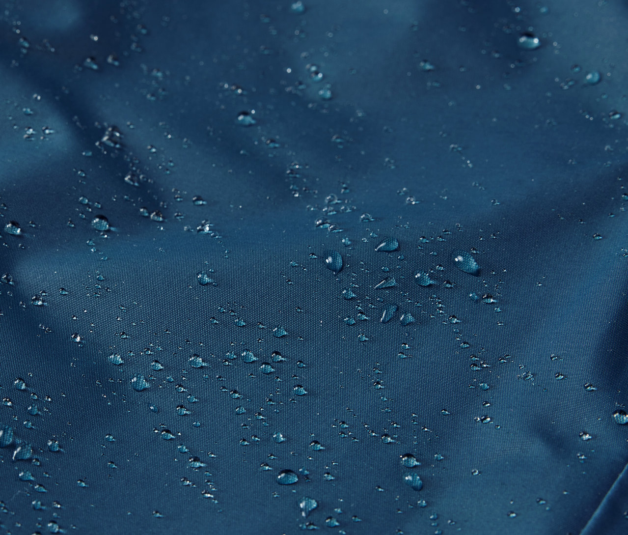 Yüzeyinde su damlaları olan çocuk termo yağmur pantolonunun yakın çekimi.