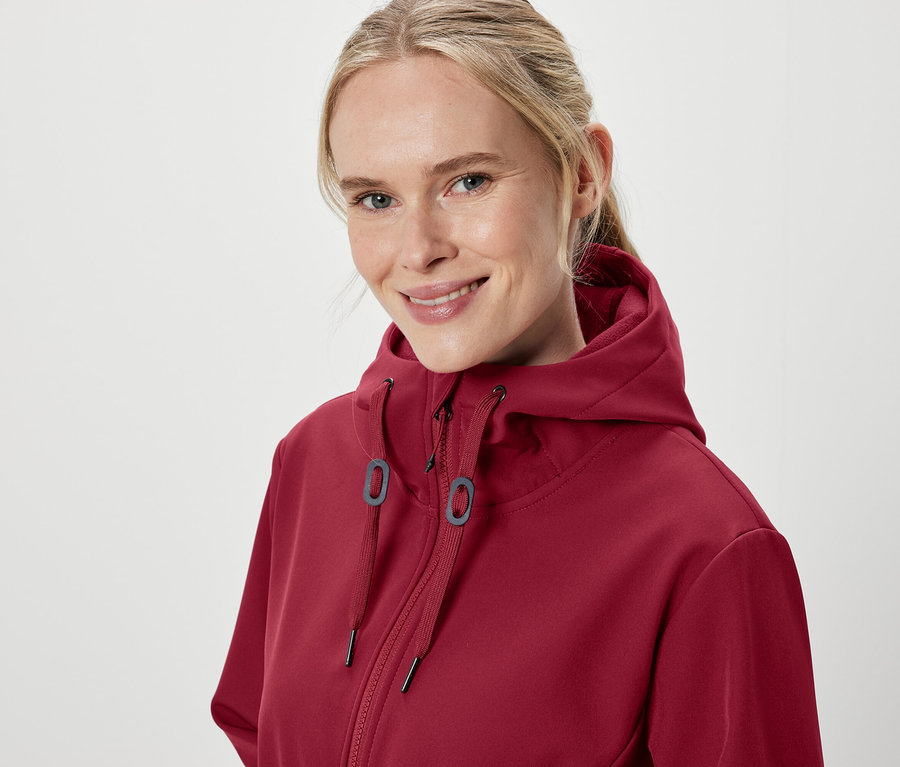 Bordo kapüşonlu bir sweatshirt giyen gülümseyen bir kadının portresi.