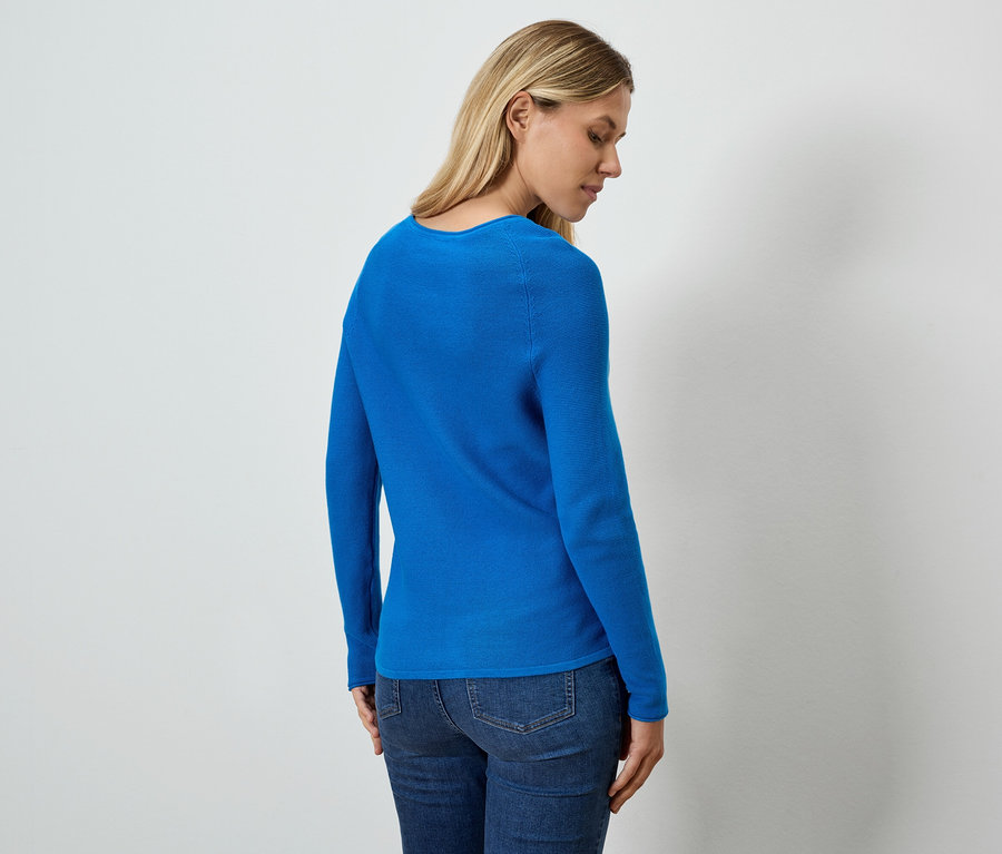 Arkadan görünen bir kadın mavi bir bluz ve kot pantolon giyiyor.