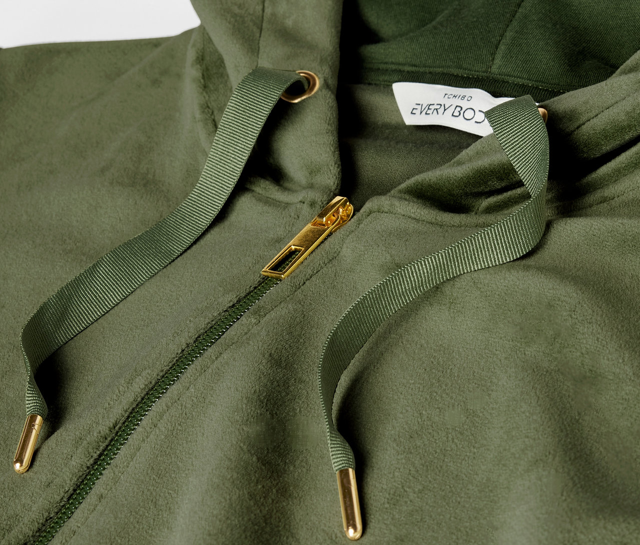 Altın fermuarlı ve ipli yeşil kapüşonlu sweatshirt detayı.
