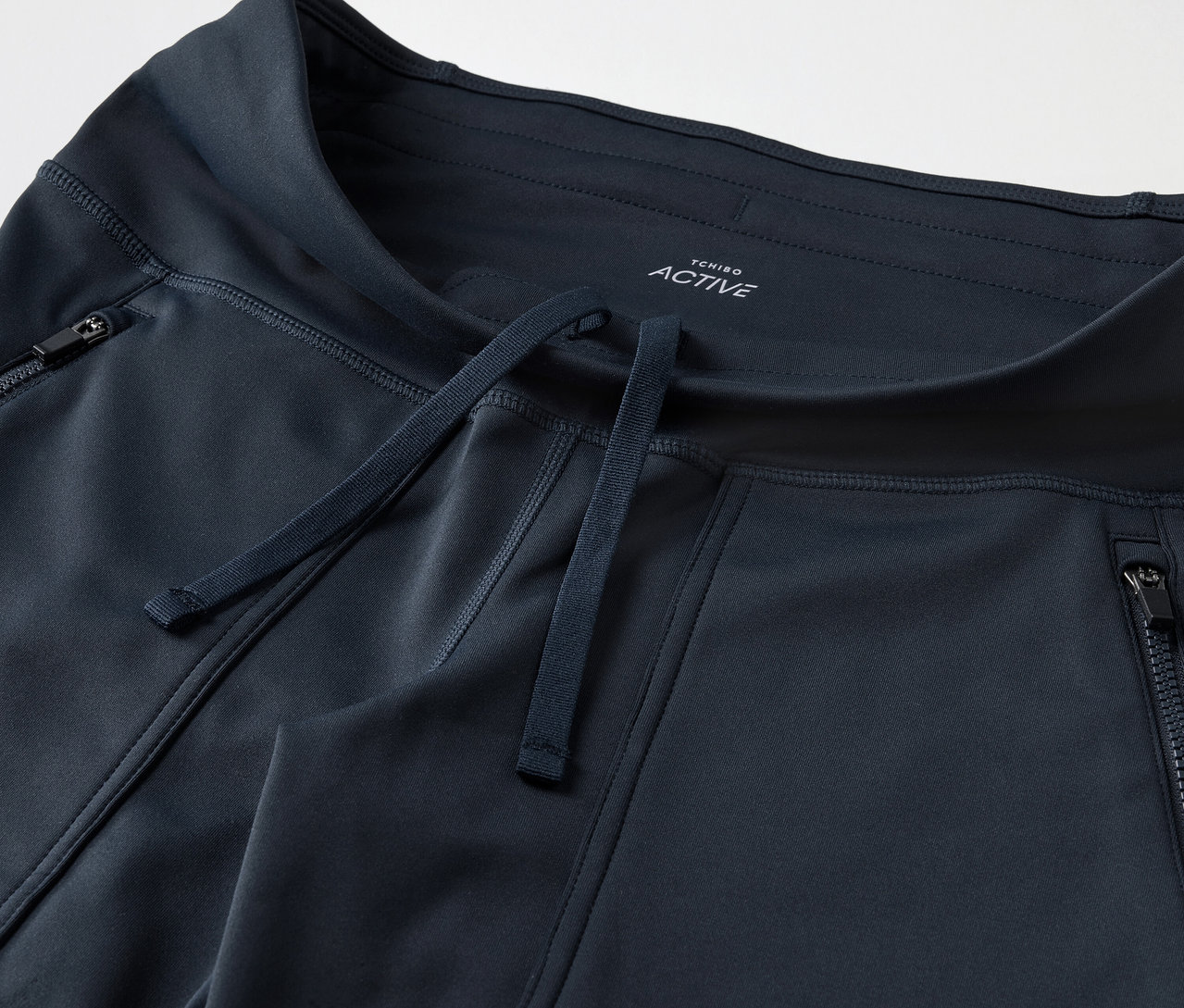 Fermuarlı cepleri ve büzgüsü olan koyu mavi eşofman altının yakın çekim görüntüsü.