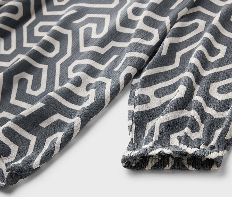 Beyaz geometrik desene sahip kırışık görünümlü gri bir bluzun detayı.